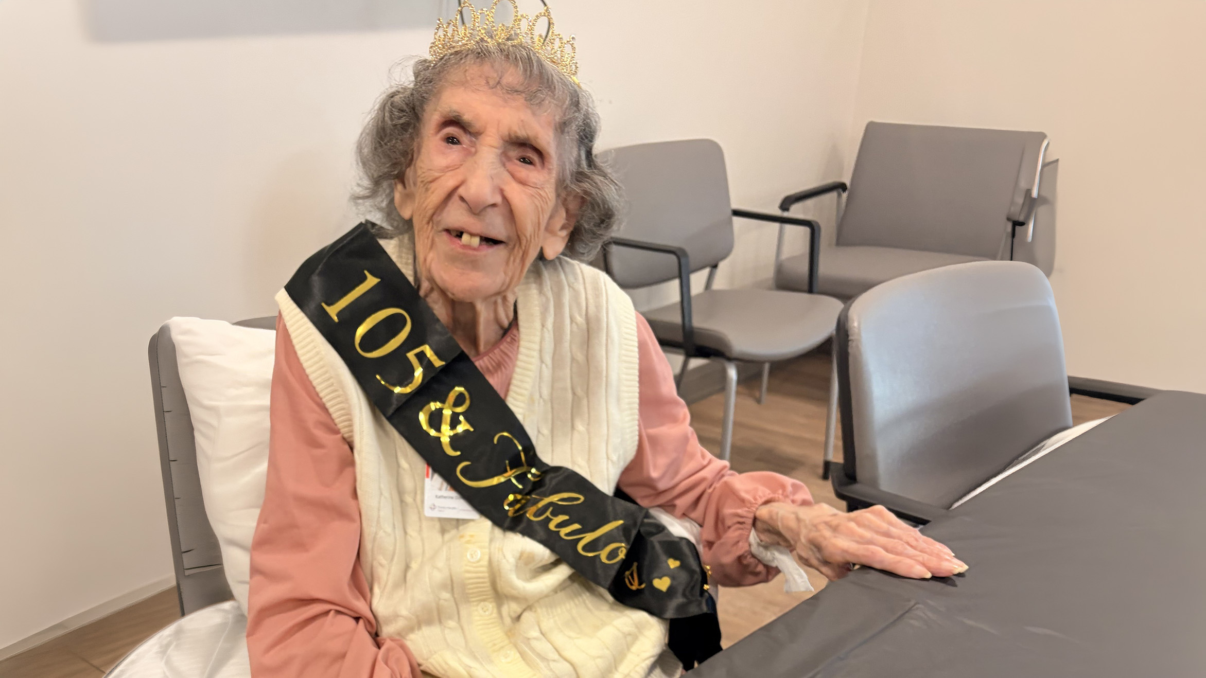 Mrs. Kay wearing a crown and 105 birthday sash during her birthday celebration at Trinity Health PACE of Pensacola.